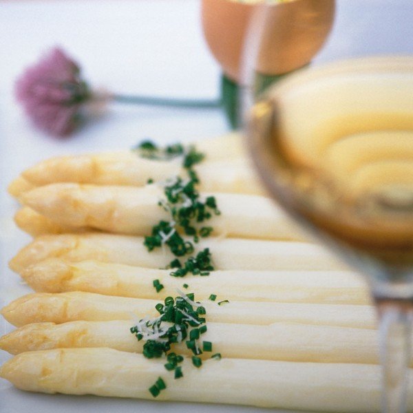 Piatto di asparagi con un bicchiere di vino bianco